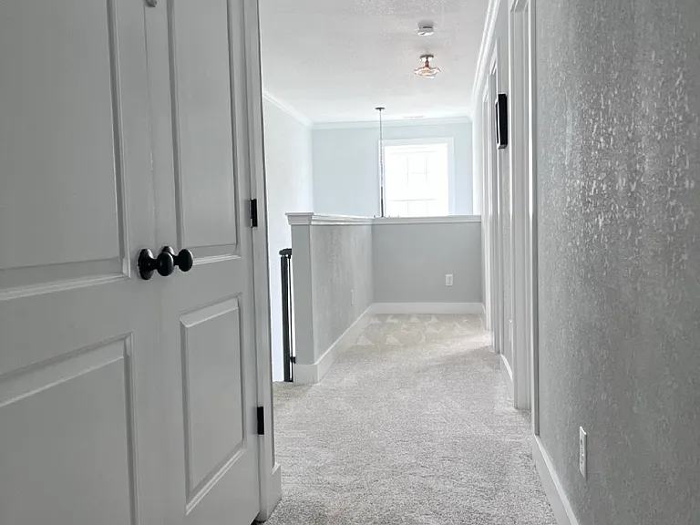 Hallway leading out of primary bedroom (double laundry doors on the left)