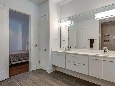 The master bath has plenty of space with white wood cabinetry, a tub, heated floors, an open shower, and an enclosed toilet area for privacy.