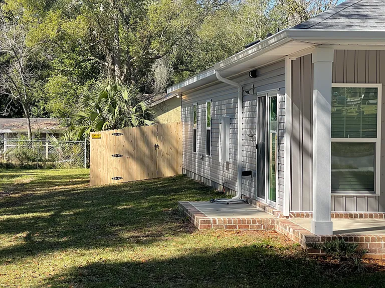 Left side of Cottage with view of fence gate,and patio with shower and entrance to kitchen -no neighbors on this side :)
