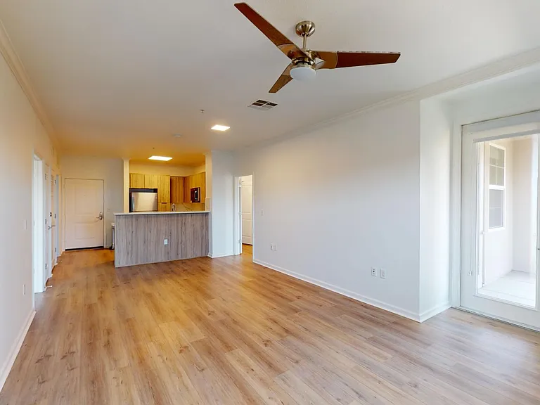 Apartment Kitchen with Stainless Steel Appliances, Dining and Living Room with Wood Style Flooring.