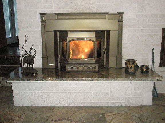 Quadra-fire wood burning insert with thermostat controlled circulating fan.