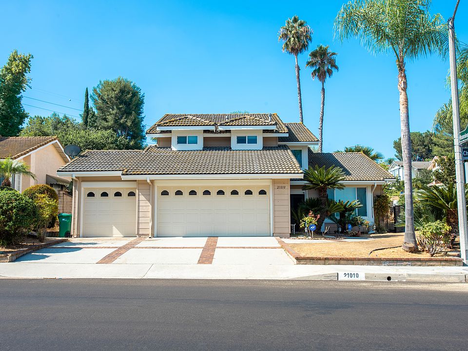Front Exterior: Beautiful two-story home on a corner lot with lush landscaping, palm trees, and a three-car garage. A perfect blend of space and privacy, this home exudes curb appeal and elegance from the moment you arrive.