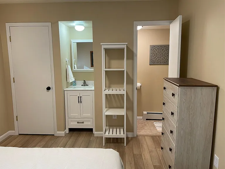 Mast bedroom, dresser and entry to bathroom with upright shower.