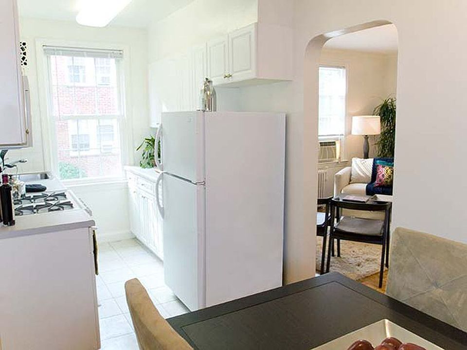 Kitchen and dining area with white appliances, white countertop, white cabinetry and hard surface flooring