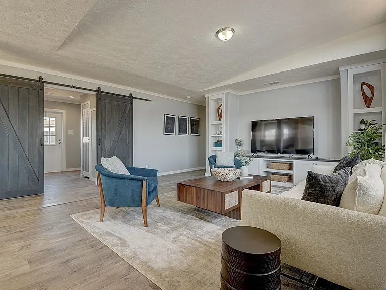 Stylish living room featuring custom built-ins, rustic sliding barn doors, and an open, airy layout_blending comfort with upscale design.