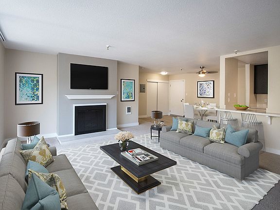 Staged and carpeted living room with fireplace and sliding door.