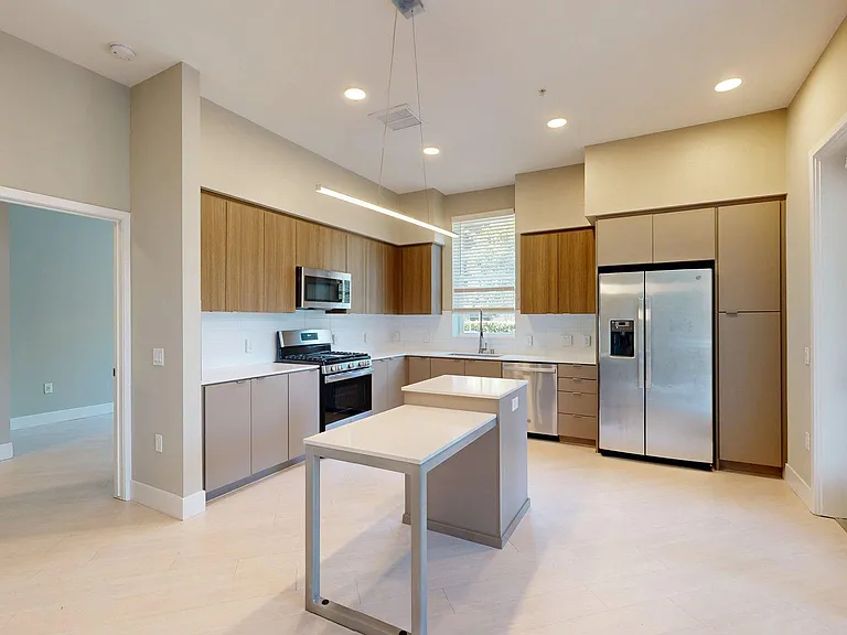 Apartment Kitchen with Stainless Steel Appliances, Quartz Countertops and Wood-Style Flooring.