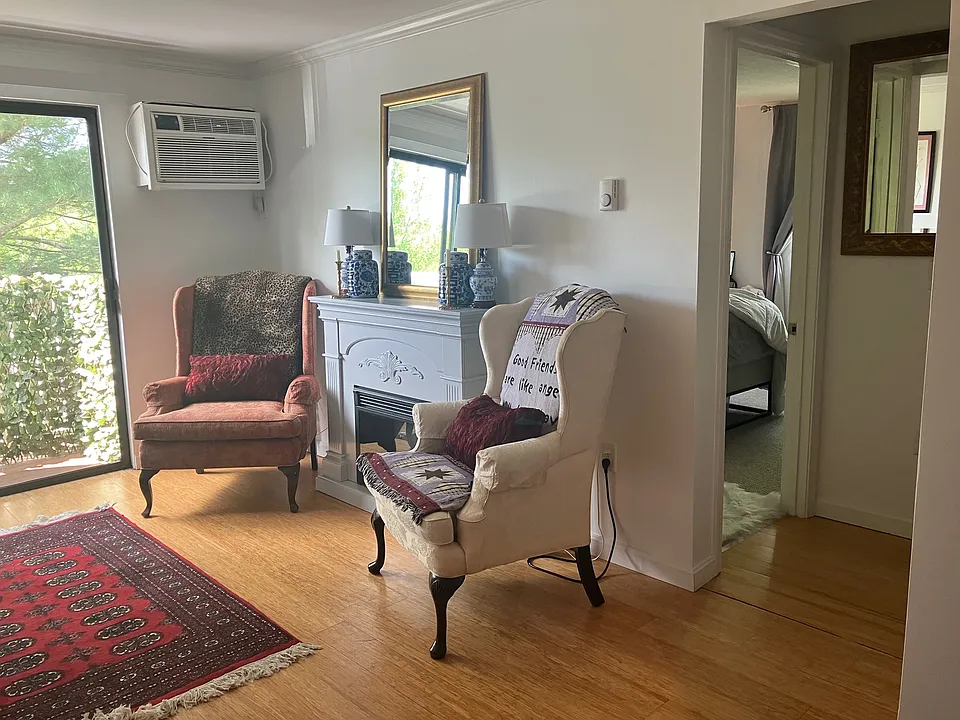 Living area (view from kitchen). Living area contains 2 chairs and 1 sofa and 2 end tables. Portable end tables are stored nearby.