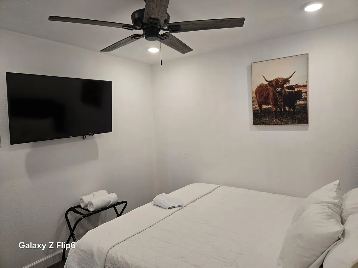 Furnished bedroom with a ceiling fan, recessed lighting, wall-mounted TV, and a comfortable bed with fresh linens. - Carnation Dr