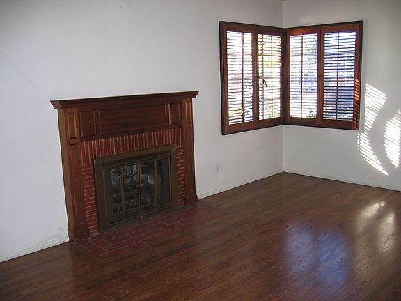 Spacious Living Room With Charming Fireplace, Hardwood Floors & Shutters