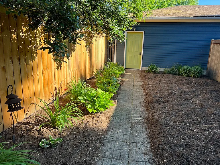 Backyard with full privacy fence and path to detached garage.
