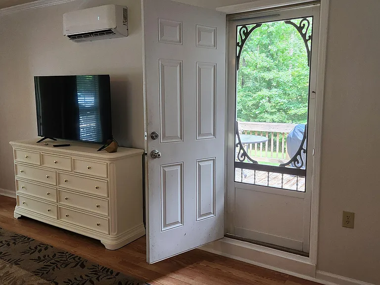 Comfortable common area with wood-look floors, a TV setup, and direct access to a screened porch/deck for easy indoor-outdoor