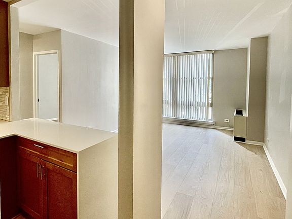 Another broad view of kitchen entry and living area; view to bedroom entry. Wide plank hardwood floors.
