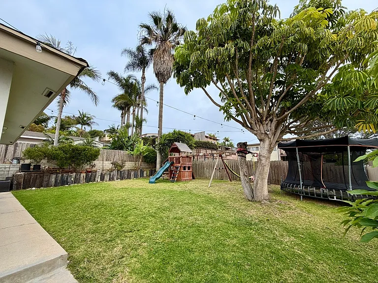 Large yard with avocado, banana, orange trees. raised garden bed on far side. Gardener included.