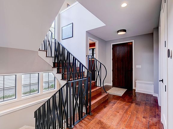 Welcome! Front entry with custom stair railing, hand scraped hardwood floors and powder room.