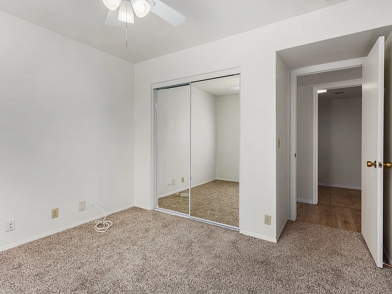 View of downstairs bedroom #1. New fan, paint, flooring, and mirrored closet doors.