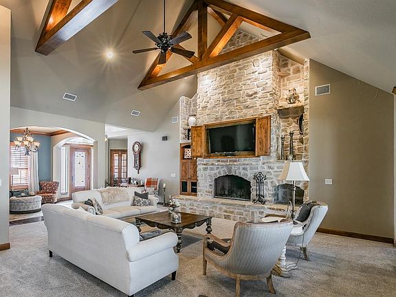 Living area featuring arched walkways, carpet floors, visible vents, and beamed ceiling