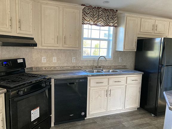 Kitchen with stainless steel double sink, gas stove, refrigerator and dishwasher.