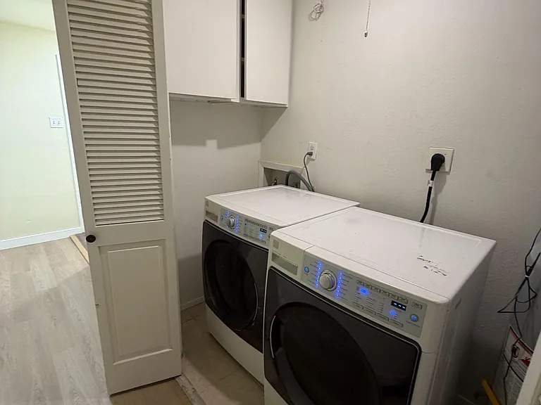 Dedicated laundry area with side-by-side washer and dryer, plus overhead cabinets for convenient storage.