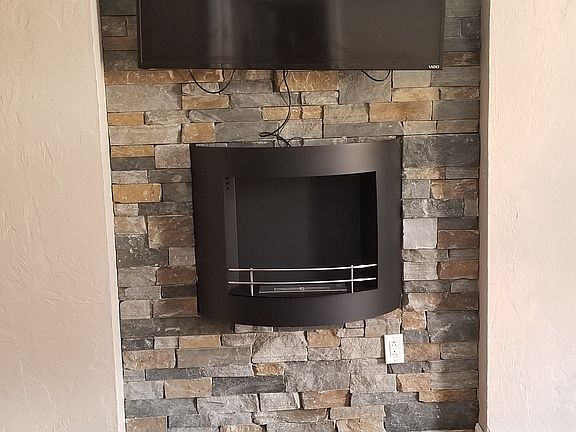 Stone wall has TV mount in place for TV. Add some Yankee candles to the faux fireplace to create a warm relaxing environment after a hard day at work.