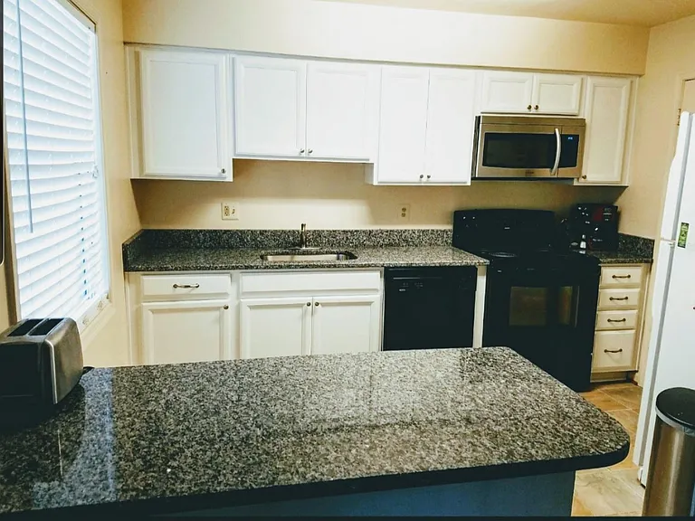 updated kitchen with white cabinets and beautiful granite countertops.