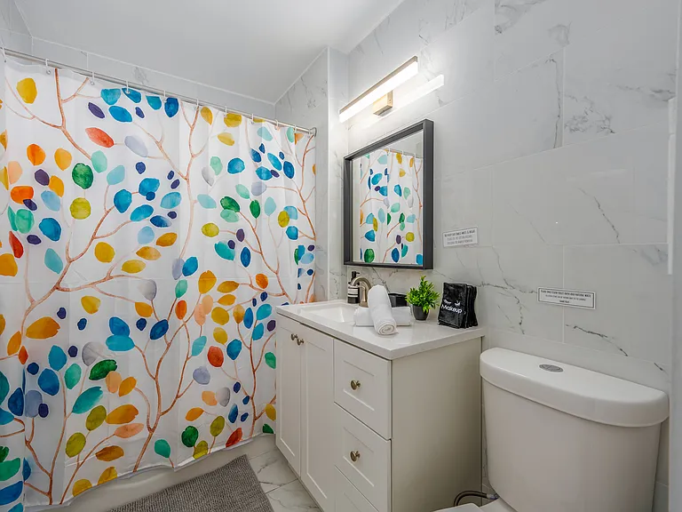 Step into this beautifully designed bathroom, a perfect blend of style and comfort. Start your day refreshed under a vibrant shower with a cheerful leafy motif that sets a positive tone.