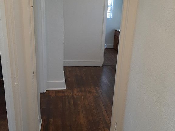 interior hallway with living room on left, looking in across kitchen through to bathroom