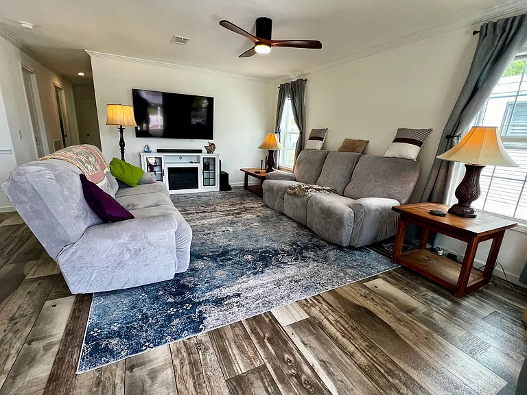 Living room. Couches have end recliners. Includes smart tv and electric fireplace, and ceiling fan.