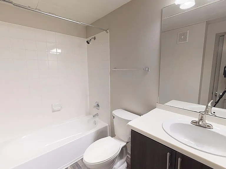 Apartment bathroom with large soaking tub and wood-style flooring.