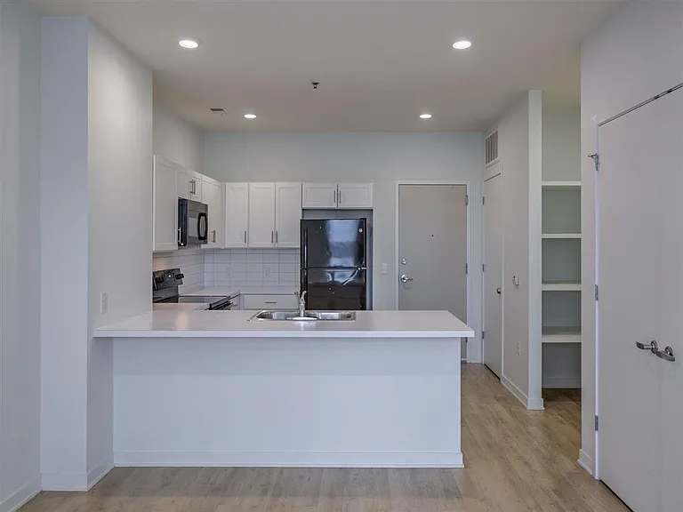 Kitchen with white cabinets and black appliances at The Rise.