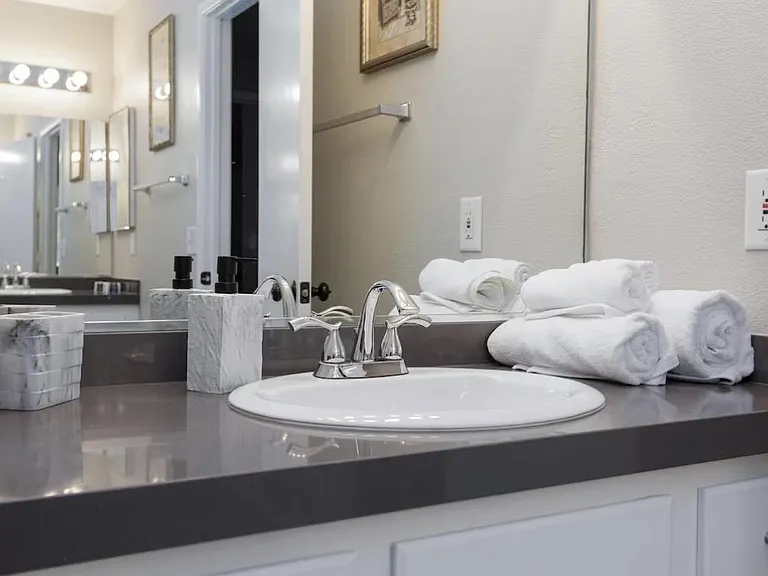 Bathroom vanity with wide countertop, large mirror, and overhead lighting for convenient daily routines and storage.