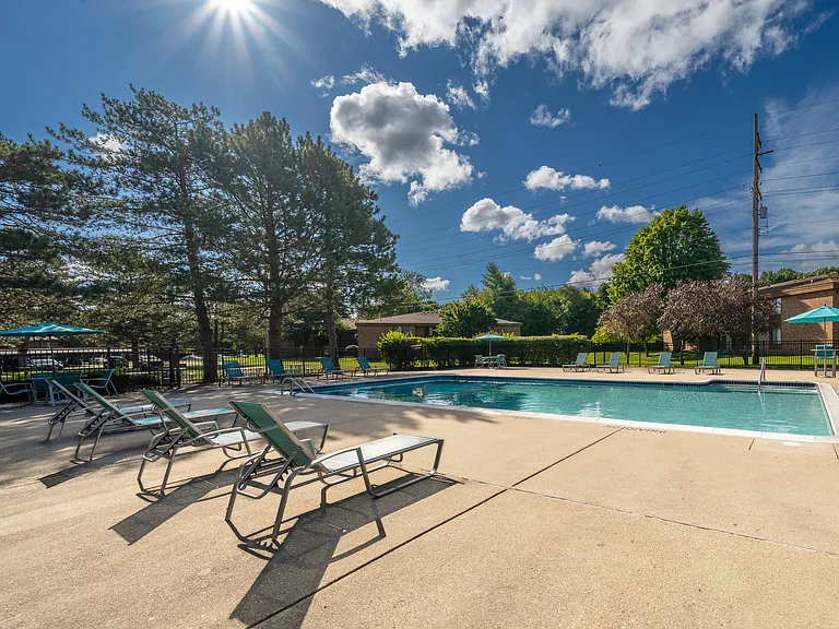 Heated pool equipped with comfy lounge chairs at Westwood Village Apartments in Westland, MI