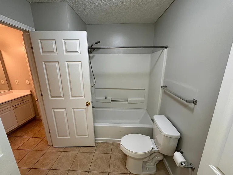 Master Bathroom shower and toilet with laundry room behind closed doors