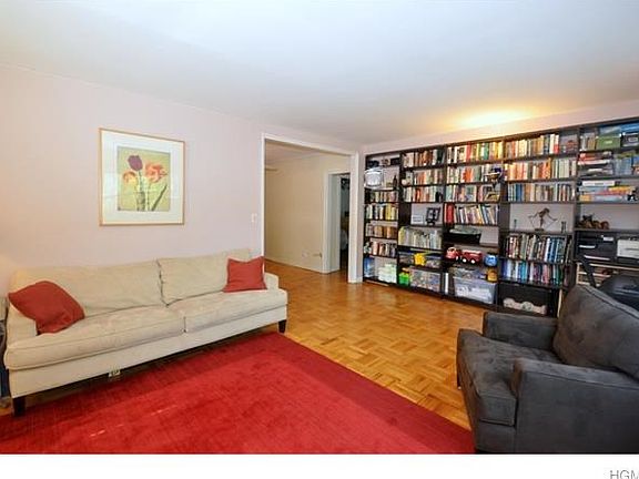 Large living room with parquet floors and two large windows featuring gorgeous tree-topped views of 