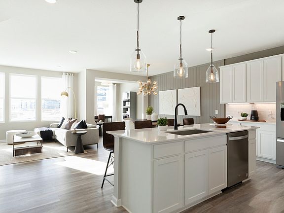 A look into the bright kitchen, gathering room, and sunroom beyond