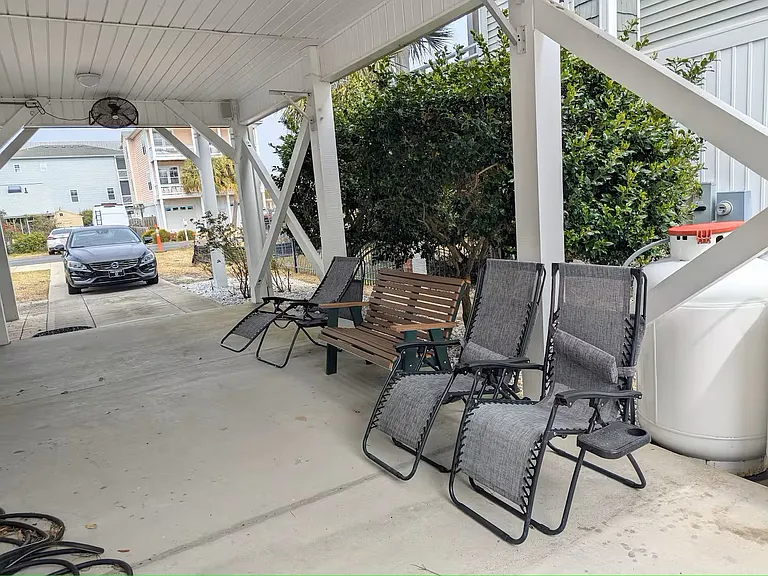 Side yard under house with seating area and built in TV on side of house