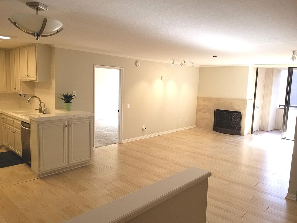 Living area from the entry hall, with a peek into the kitchen, one bedroom, and the balcony.