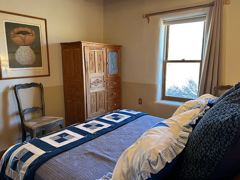 Nambe Casita looking towards window and additional armoire. Window looks out to field and acequia.