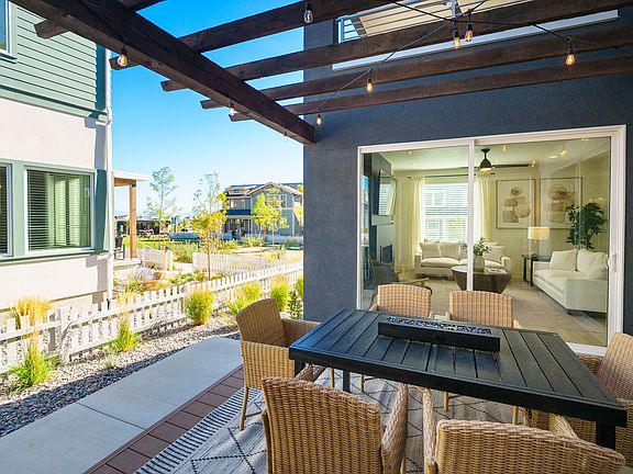 A modern patio from the Contempo Collection features a black dining table and wicker chairs under a