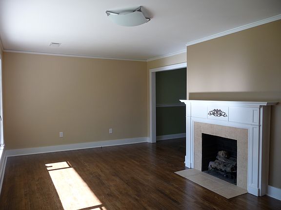 Spacious living room includes original mantle and hardwood floors
