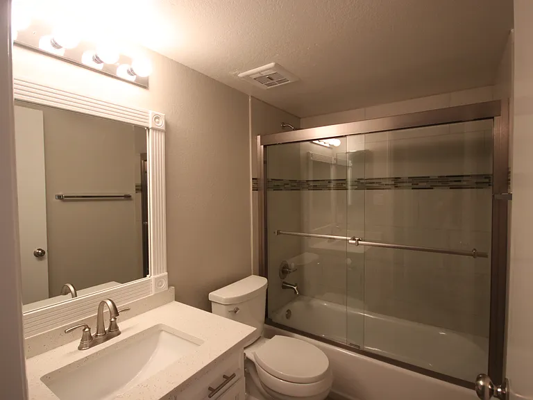 Your second full bath beautifully glass-enclosed, quartz-top sink, and toilet.