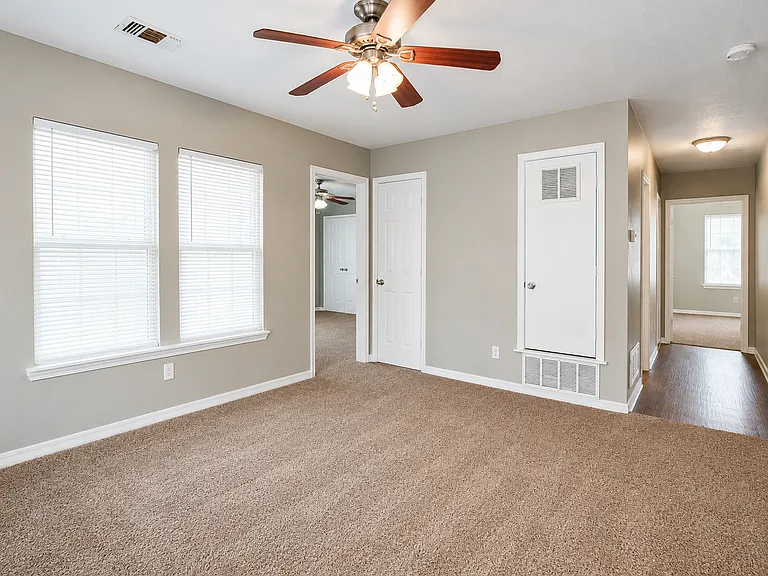 Entry Living Area with the entrance to Jack & Jill Suite 2 on the left, the Primary Suite on the right, and a hallway leading to the shared kitchen, laundry room, and additional bedrooms.