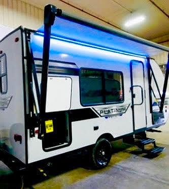 This photo showcases the awning which is operated with a press of a botton and its partially open here where the Studio Camper was built. YEs, these are LED lights. You can see the steps and grab bar that opens a secure/double featured door. To the lef