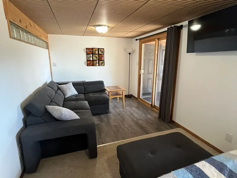 Bedroom and sitting area with full size pull out couch, sliding doors to the beautiful deck, and a 45" Smart TV on a wall mounted swivel