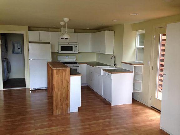 Kitchen with gas range, refrigerator, dishwasher. Door at left leads into laundry room/pantry.
