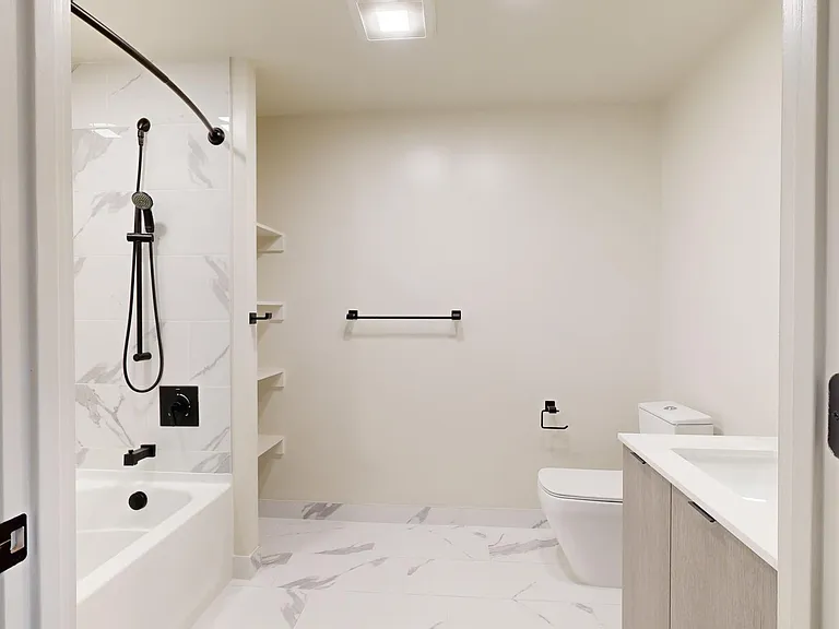 Apartment bathroom with tile flooring and LED vanity mirror.