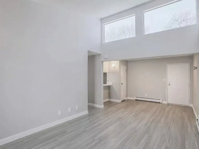 Bright and airy room with modern wood flooring, high ceilings, and large windows flooding the space with natural light.