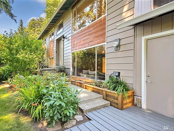 View of front door, (middle) custom cedar planter boxes along side walkway to front door, Garage man door (right)