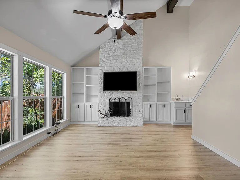 Living room with custom built-in cabinetry and a bar area with a quartz countertop. TV comes with the property.