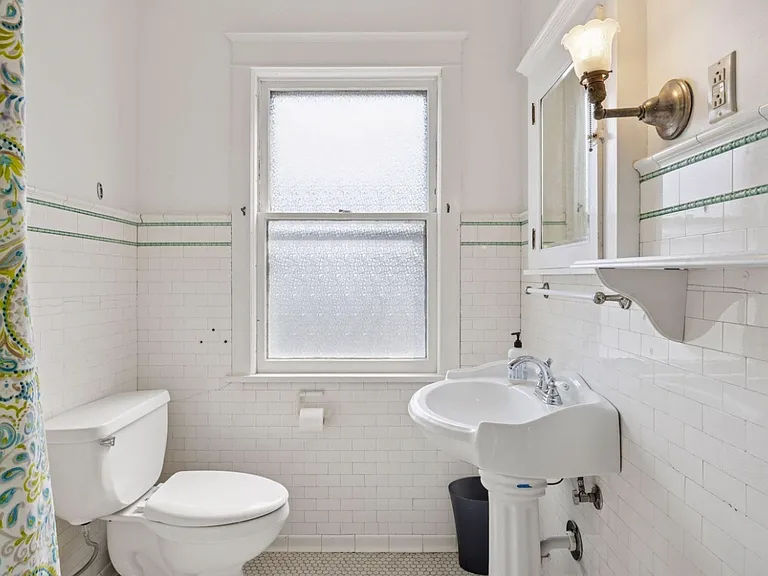 Full bathroom with detailed tilework hinting at the history of this home. More natural light, a big bonus for a bathroom!